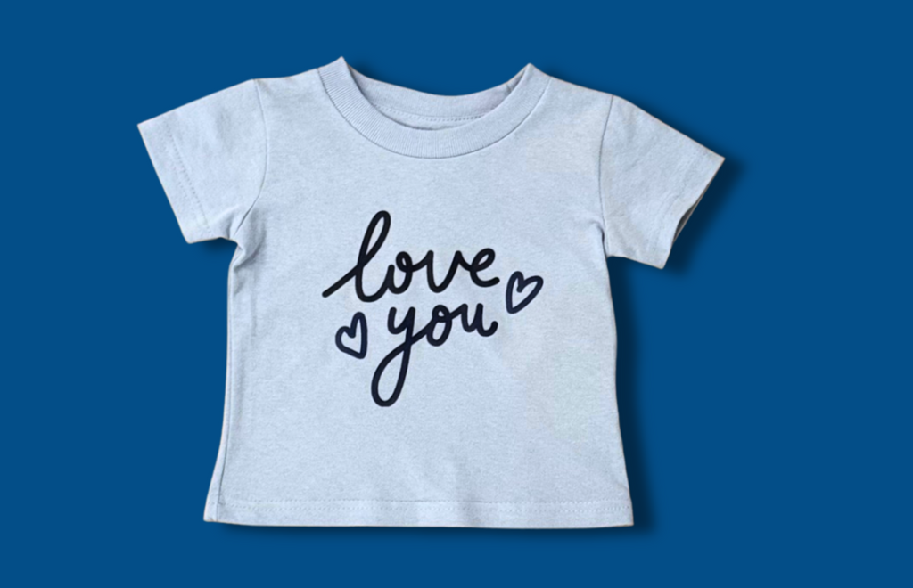 Image on dark blue of a light blue baby tee that says Love You and has two small heart outlines in dark blue lettering